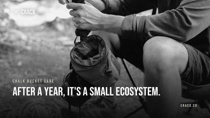A climber holding a chalk bag beside a coiled rope and approach shoes