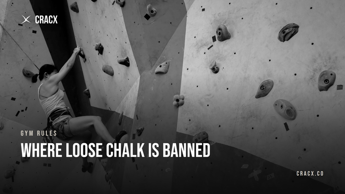 Where loose chalk is banned: a boulderer with chalked hands on an indoor climbing gym wall