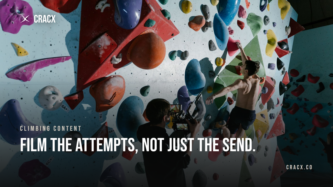 A videographer with a cinema camera filming a climber reaching for a hold on an indoor bouldering wall