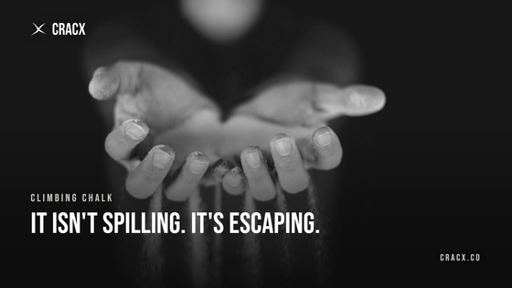 Climbing chalk streaming out between a climber's fingers against a dark background