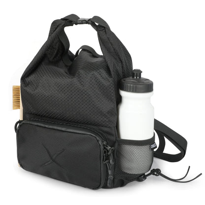 CRACX Ascend chalk bucket in three-quarter view loaded with a water bottle in the mesh pocket and a brush on the flank