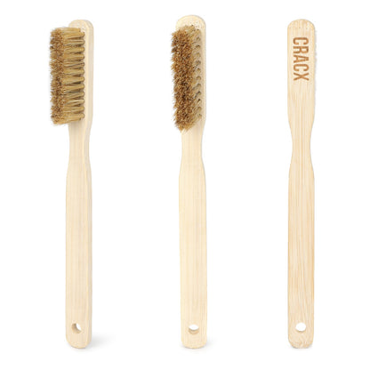 The CRACX bamboo climbing brush shown from three angles, boar bristle head and CRACX branding burned into the handle