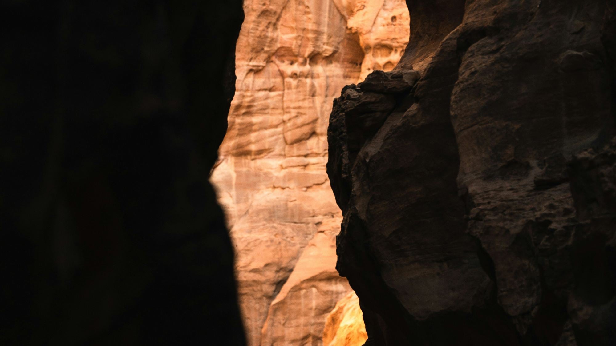 A climber small against the warm walls of a narrow desert canyon